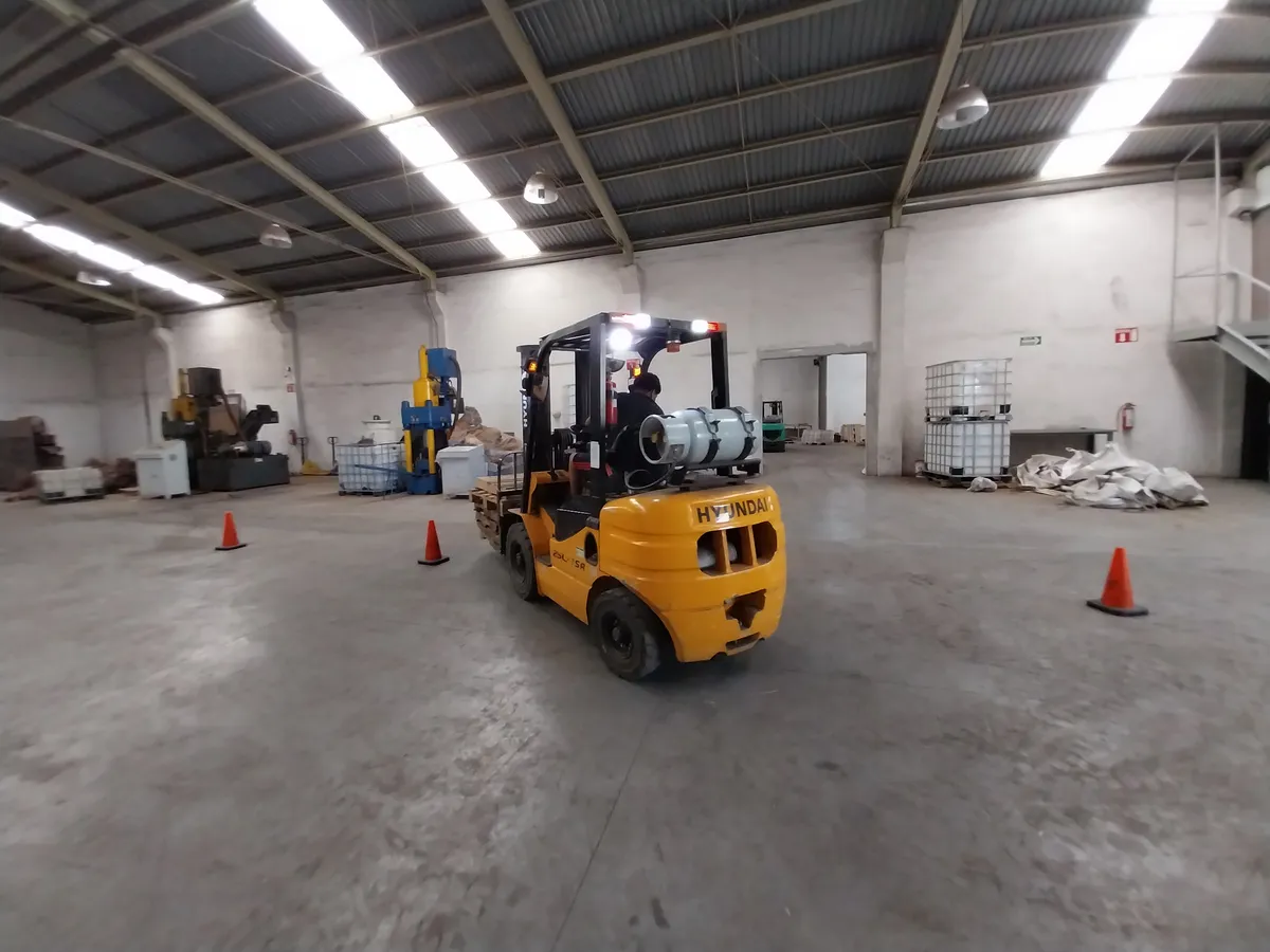 Práctica de circuito con conos dentro de planta industrial en el curso de montacargas